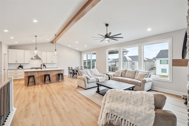 living room with vaulted ceiling with beams, ceiling fan, and light hardwood / wood-style flooring