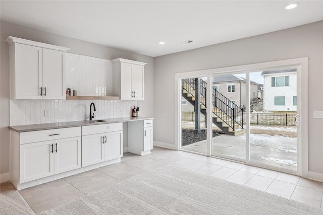 kitchen with white cabinets, light tile patterned floors, decorative backsplash, and sink