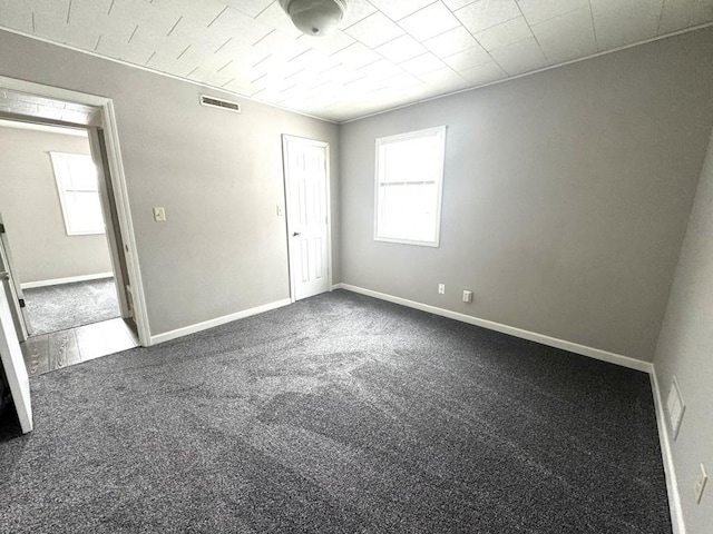unfurnished room with baseboards, carpet flooring, and visible vents