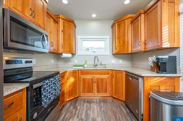 kitchen featuring dark hardwood / wood-style floors, light stone counters, sink, and appliances with stainless steel finishes