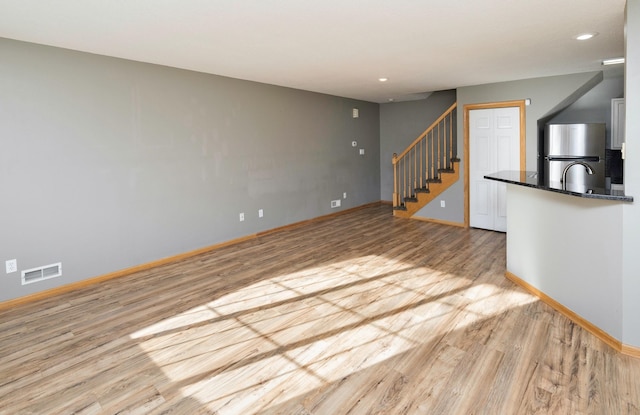 unfurnished living room with light hardwood / wood-style flooring and sink