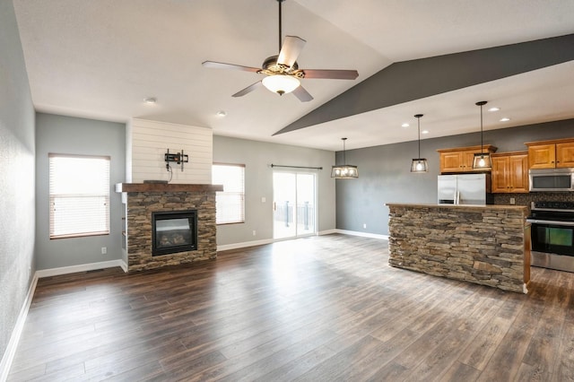 living room featuring vaulted ceiling, a stone fireplace, ceiling fan, and dark wood-type flooring