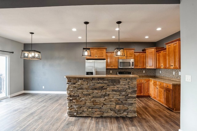 kitchen with pendant lighting, a center island, dark wood-type flooring, decorative backsplash, and appliances with stainless steel finishes