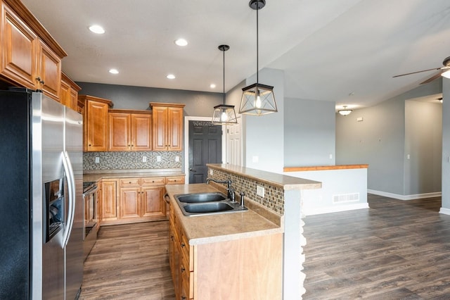 kitchen featuring sink, stainless steel appliances, decorative backsplash, pendant lighting, and a kitchen island with sink