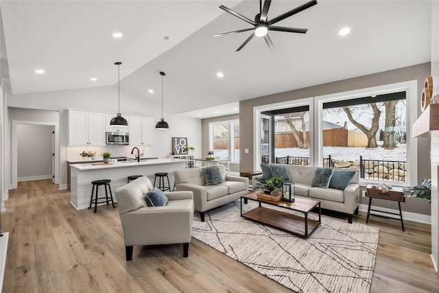 living room with a wealth of natural light, ceiling fan, lofted ceiling, and light wood-type flooring