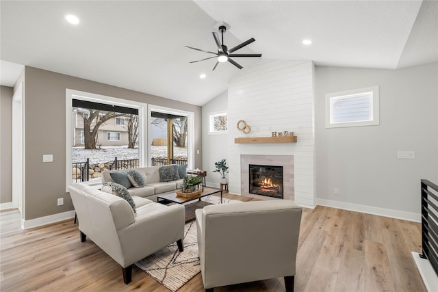 living room with a fireplace, light wood-type flooring, ceiling fan, and lofted ceiling