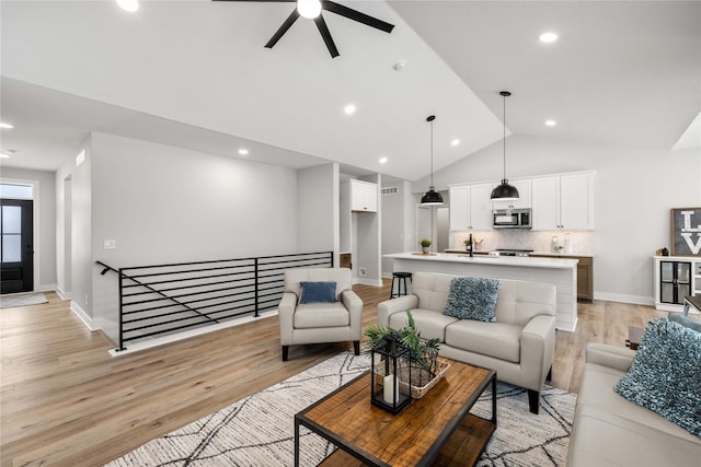 living room with light hardwood / wood-style floors, vaulted ceiling, and ceiling fan