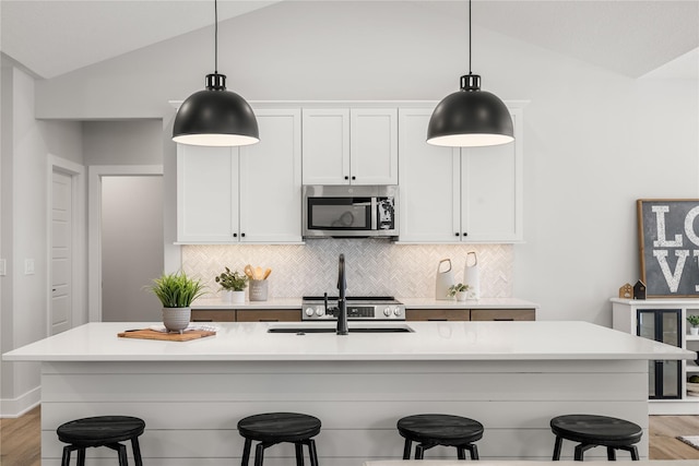 kitchen with a kitchen breakfast bar, white cabinetry, lofted ceiling, and a kitchen island with sink