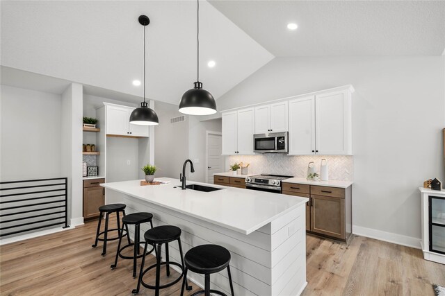 kitchen with stainless steel appliances, white cabinetry, a kitchen island with sink, and sink