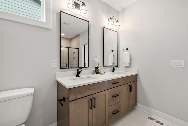 bathroom featuring tile patterned floors, vanity, toilet, and a shower with shower door