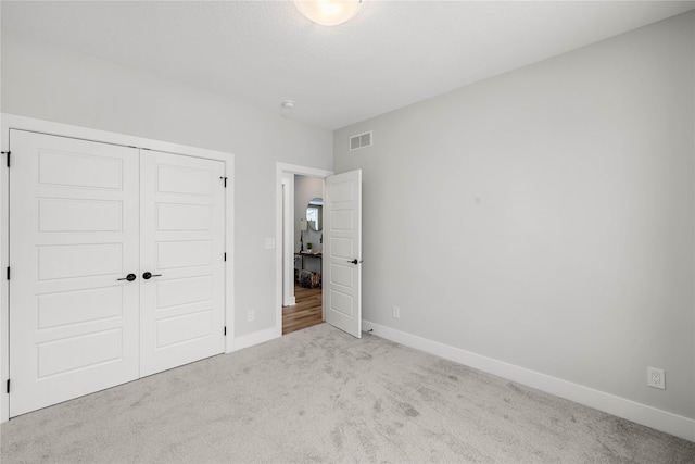 unfurnished bedroom featuring light carpet and a closet