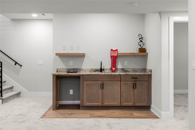 bar with light stone countertops, light carpet, and sink