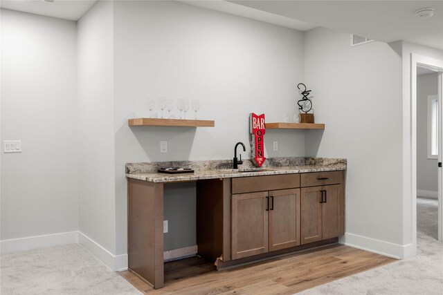 kitchen featuring light stone counters, light colored carpet, and sink