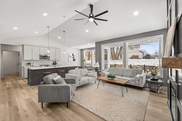 living room featuring ceiling fan, vaulted ceiling, and light hardwood / wood-style flooring