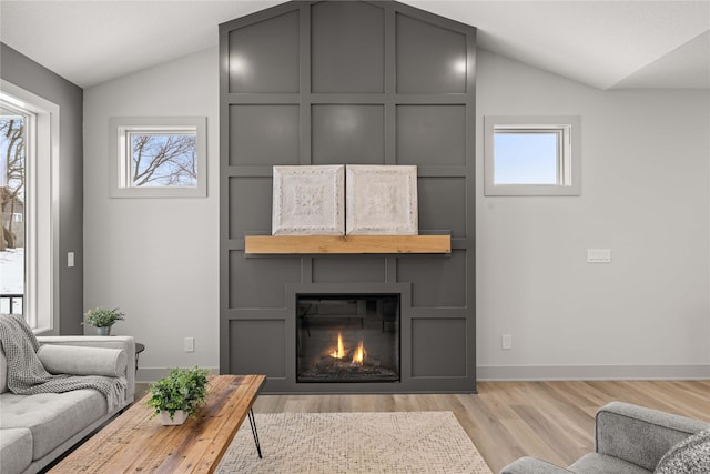 living room with a fireplace, lofted ceiling, and light wood-type flooring