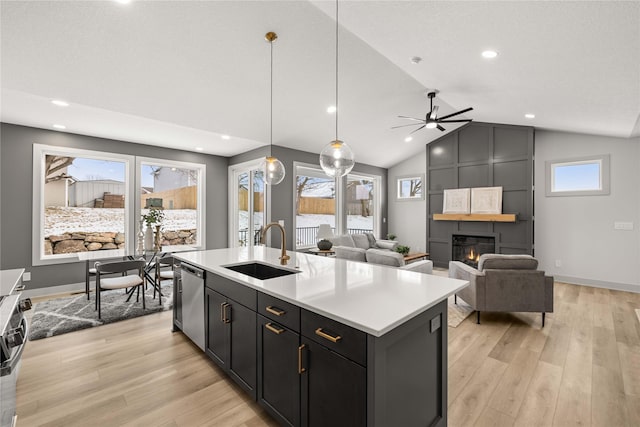 kitchen with a large fireplace, ceiling fan, sink, light hardwood / wood-style flooring, and dishwasher