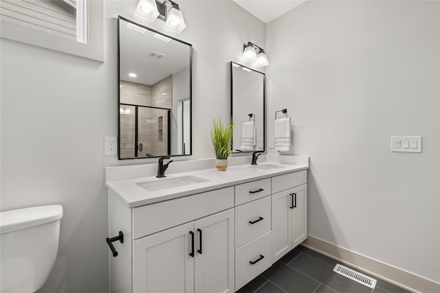 bathroom featuring tile patterned flooring, vanity, toilet, and a shower with door