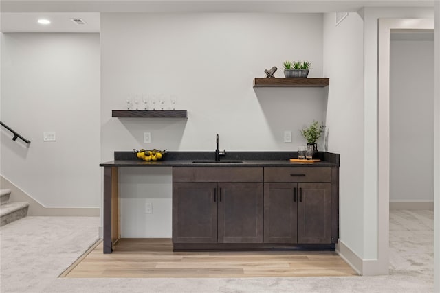 bar with light carpet, sink, and dark brown cabinets