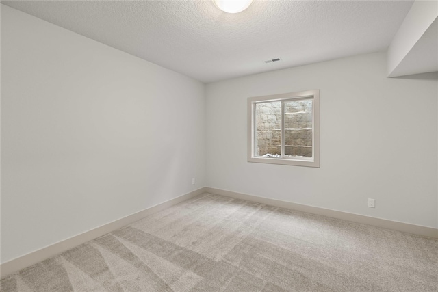 carpeted empty room featuring a textured ceiling