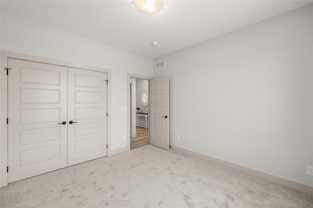 unfurnished bedroom featuring light carpet and a closet