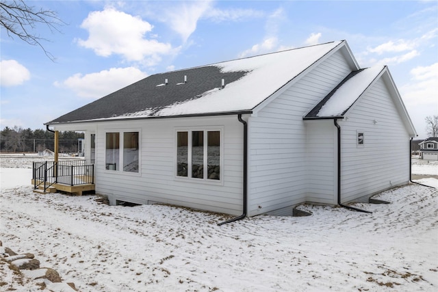 snow covered back of property with a wooden deck