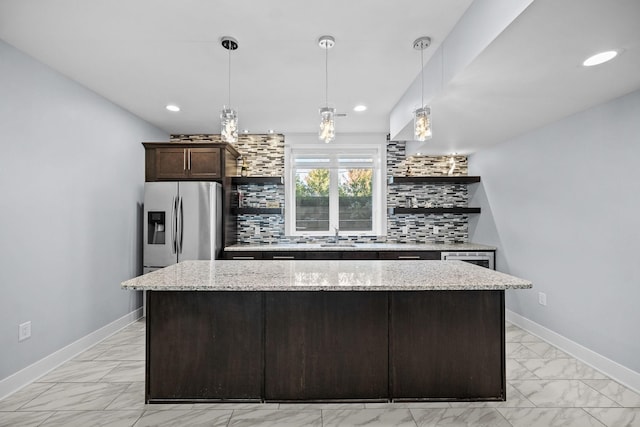 kitchen with light stone countertops, pendant lighting, tasteful backsplash, and stainless steel fridge with ice dispenser