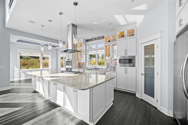 kitchen featuring a center island, island range hood, light stone counters, white cabinetry, and stainless steel appliances