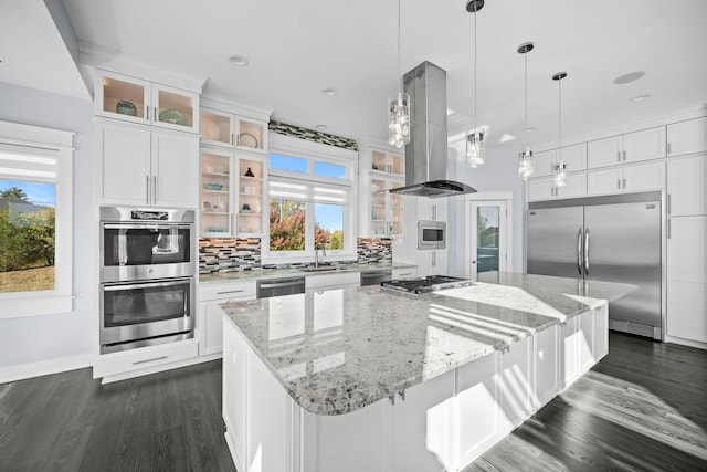 kitchen featuring a spacious island, built in appliances, tasteful backsplash, island range hood, and white cabinetry