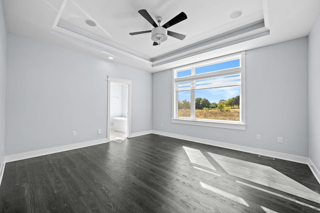 empty room with dark hardwood / wood-style floors, a raised ceiling, and ceiling fan