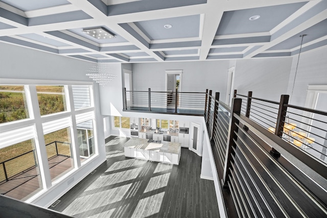 corridor featuring coffered ceiling, plenty of natural light, a chandelier, and dark hardwood / wood-style floors