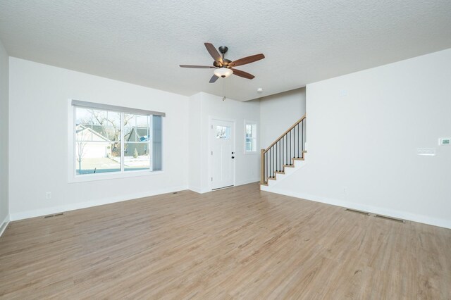 unfurnished living room featuring a textured ceiling, light hardwood / wood-style flooring, and ceiling fan