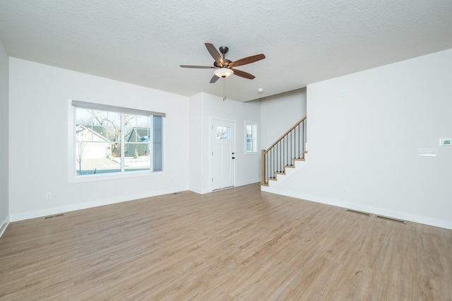 unfurnished living room featuring ceiling fan, a textured ceiling, and light wood-type flooring