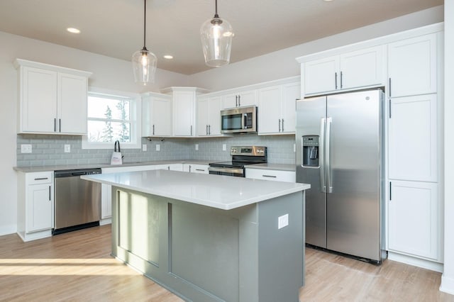 kitchen featuring a center island, decorative backsplash, decorative light fixtures, white cabinetry, and stainless steel appliances