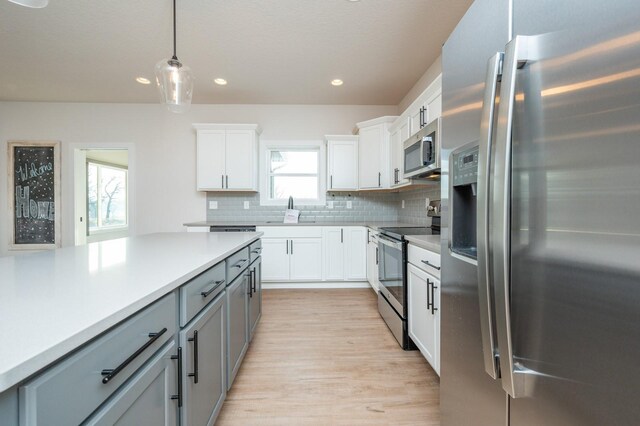 kitchen featuring gray cabinetry, plenty of natural light, white cabinets, appliances with stainless steel finishes, and decorative light fixtures