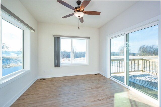 unfurnished room with a wealth of natural light, ceiling fan, and light wood-type flooring