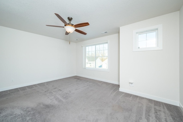 carpeted empty room featuring ceiling fan, a healthy amount of sunlight, and a textured ceiling