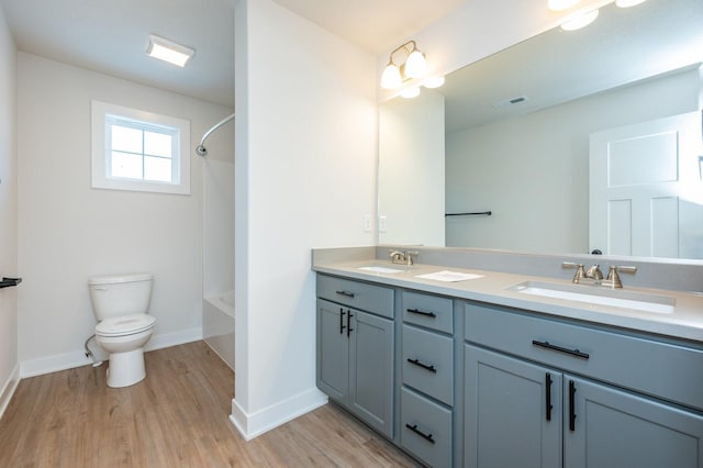 full bathroom with hardwood / wood-style floors, vanity, shower / bath combination, and toilet