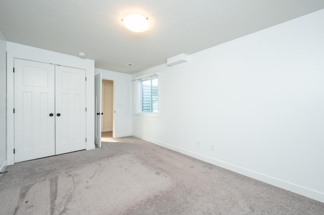 unfurnished bedroom with light carpet, a textured ceiling, and a closet