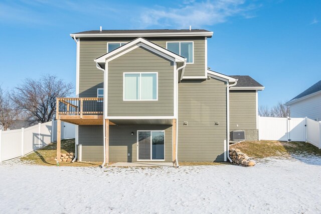 snow covered back of property featuring a deck and central air condition unit