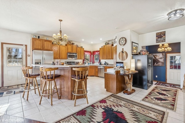 kitchen with light tile patterned flooring, hanging light fixtures, a notable chandelier, a kitchen island, and stainless steel appliances