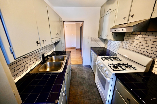 kitchen with white range with gas stovetop, backsplash, white cabinetry, and sink