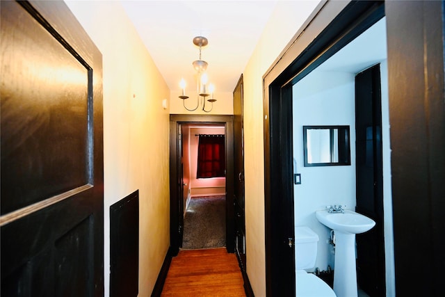 hallway with sink, dark wood-type flooring, and a chandelier