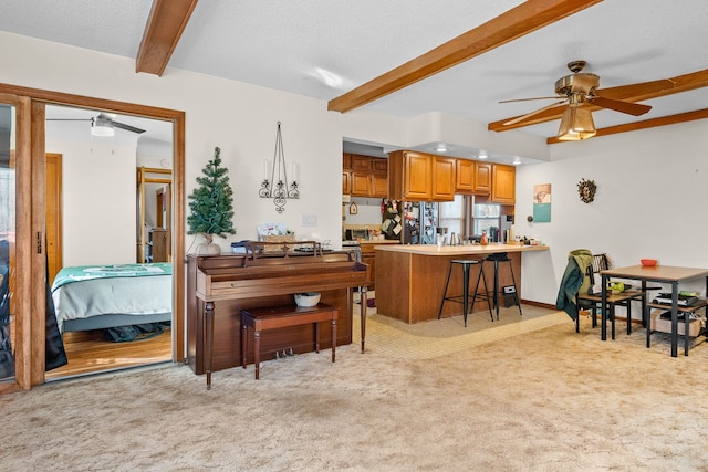 misc room featuring ceiling fan, light colored carpet, and beam ceiling