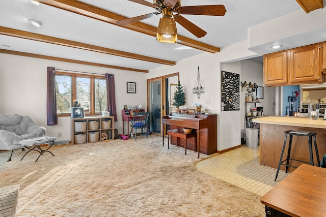 kitchen with light carpet, a textured ceiling, a kitchen breakfast bar, ceiling fan, and beam ceiling