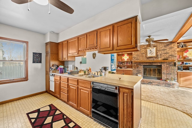 kitchen featuring sink, black dishwasher, kitchen peninsula, ceiling fan, and a fireplace