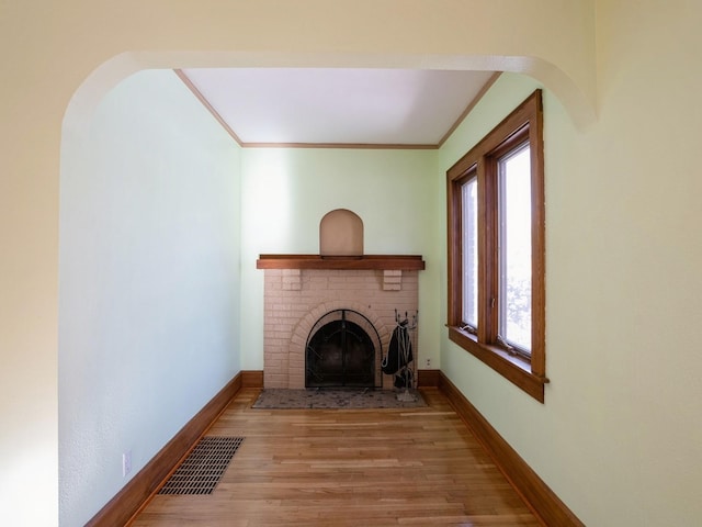 living room with wood-type flooring, a fireplace, and ornamental molding