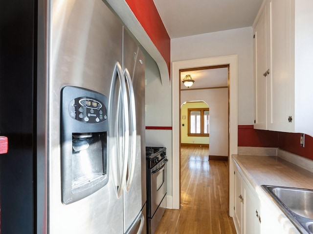 kitchen featuring appliances with stainless steel finishes, light wood-type flooring, white cabinetry, and sink