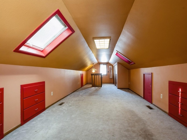 bonus room with light colored carpet and vaulted ceiling with skylight