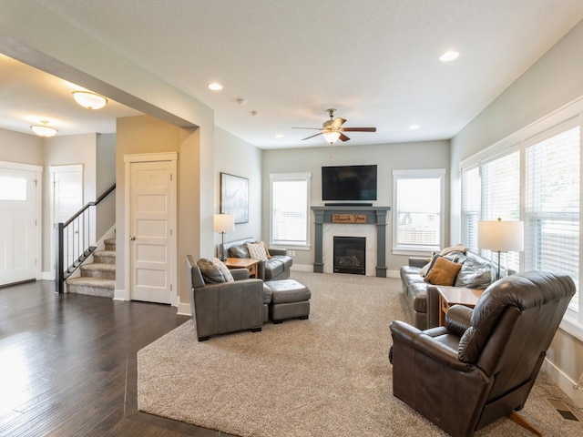 living room featuring ceiling fan, dark hardwood / wood-style floors, and a tiled fireplace