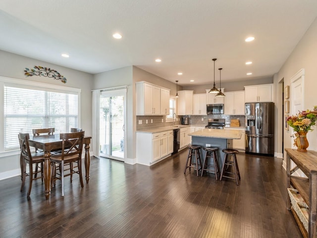 kitchen with pendant lighting, a center island, white cabinetry, and appliances with stainless steel finishes